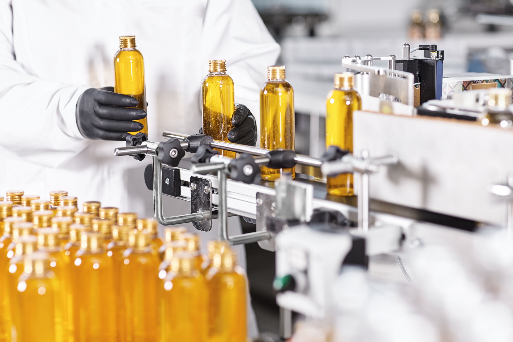 Automated process of production new cosmetic products on big modern factory. Scientist standing near